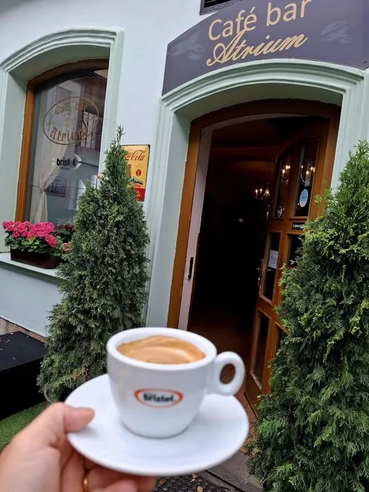Vchod do Café baru Atrium s šálkem kávy Bristot